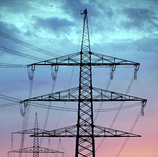 A series of electricity pylons are silhouetted against a twilight sky with clouds, symbolizing the power behind smart homes and intelligent services.