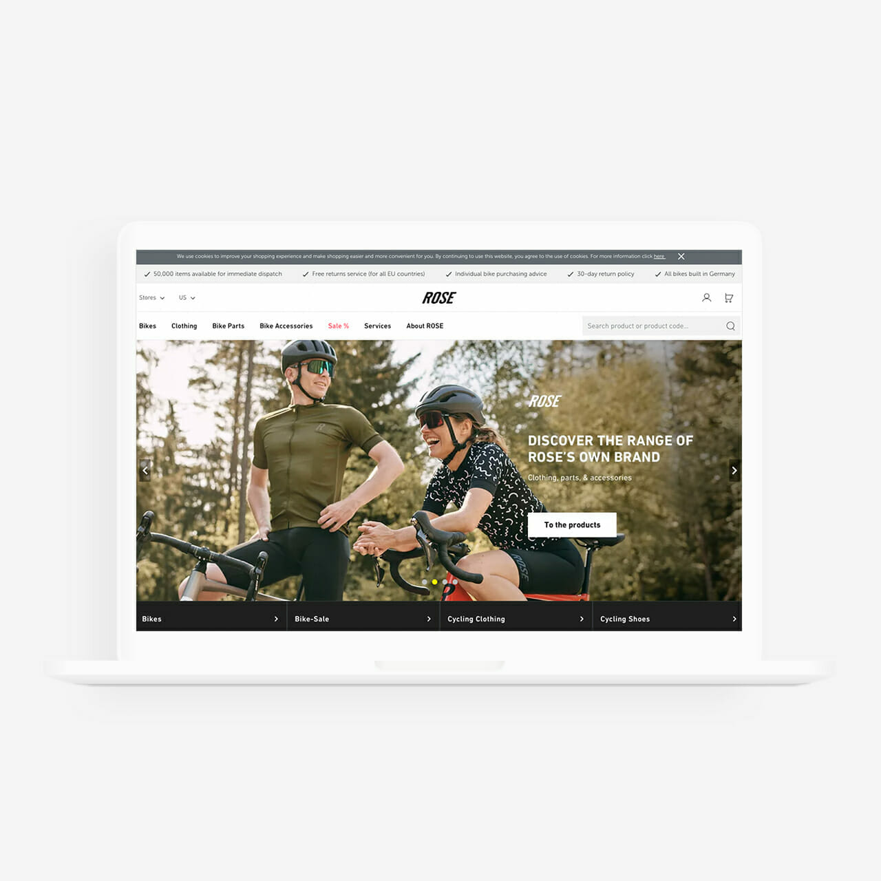 A laptop displays a website featuring two cyclists wearing helmets and sunglasses. The site promotes various cycling products including bikes, bike gear, cycling clothing, and accessories.