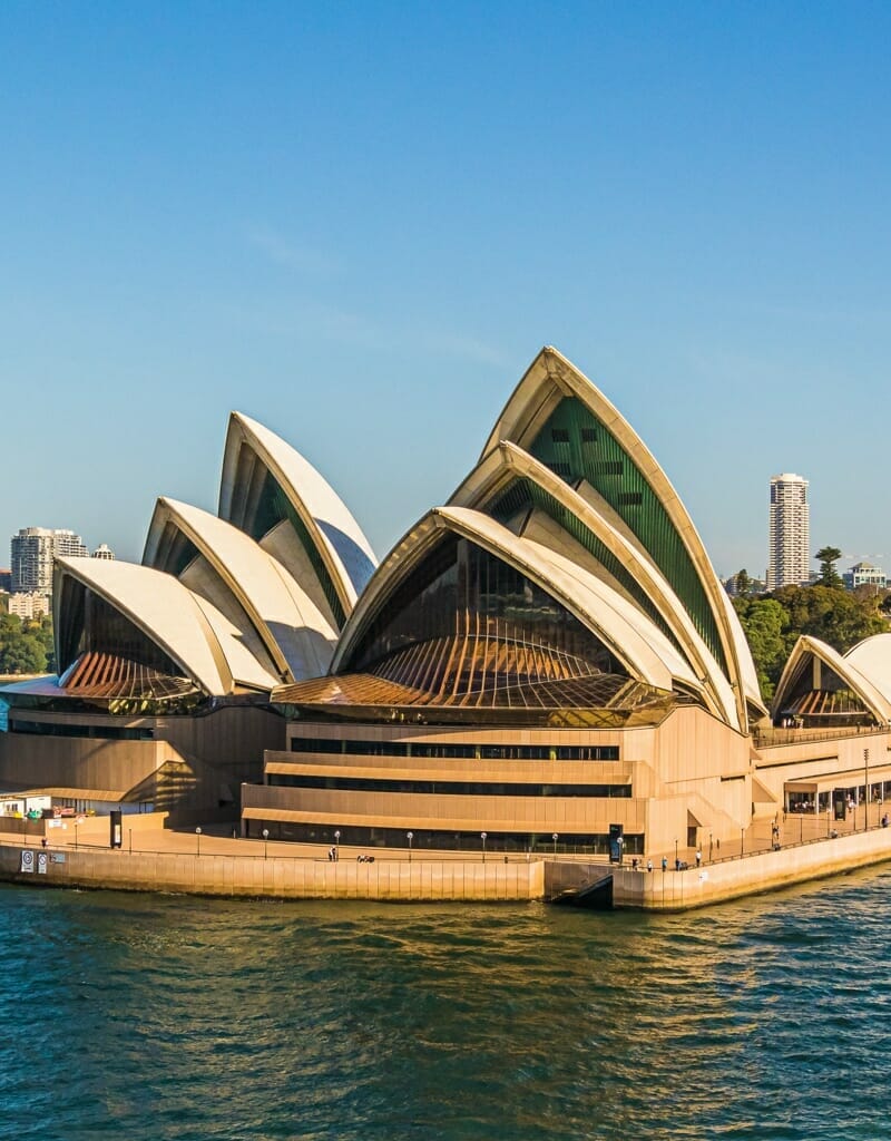 Panoramic view of Sydney Harbour featuring the Sydney Opera House to the left, skyscrapers in the background, and ferries on the water—a quintessential scene of Australia.