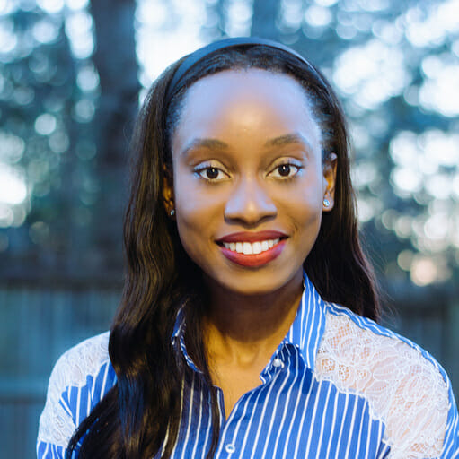 A woman with long dark hair and a radiant smile, wearing a blue and white patterned blouse, stands outdoors with blurred trees in the background, exuding the same seamless efficiency as an Order Management System.