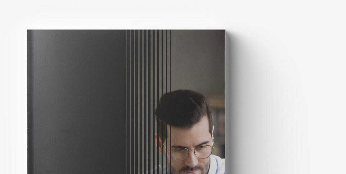 Person with glasses working behind a black striped glass partition, focusing intently on the delayed replatforming project.