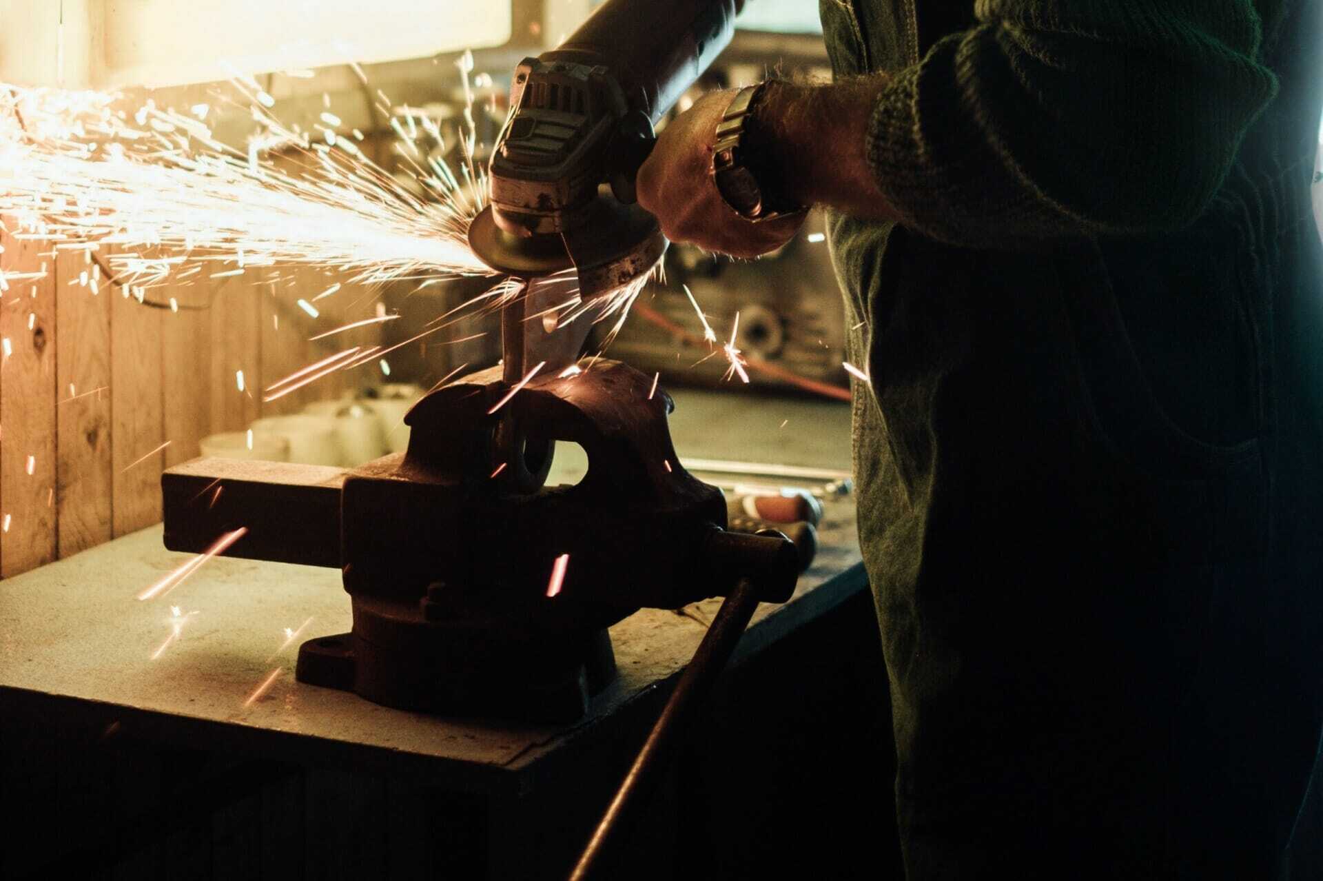 Person using an angle grinder on metal in a workshop, with sparks flying while integrating ERP systems for better workflow.